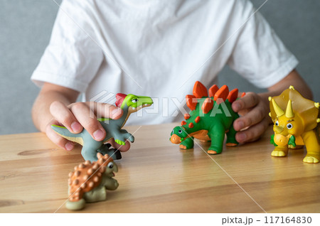 Child Playing with Dinosaur Toys on Wooden Table 117164830
