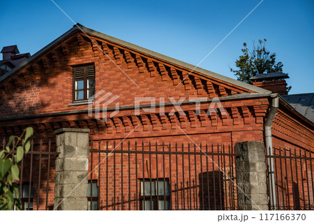 An old, renovated, brick house, behind a fence An old, renovated, brick house, behind a fence 117166370