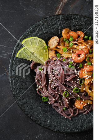 Close-up view of a plate with spicy black rice noodles, shrimps and mushrooms Close-up view of a plate with spicy black rice noodles, shrimps and mushrooms 117168358