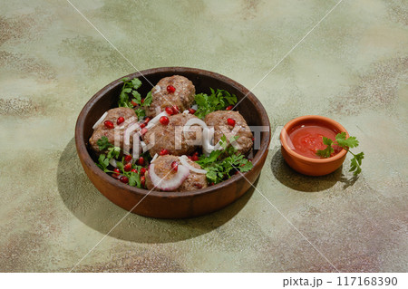 Fried beef or lamb patties wrapped in fat gut - Apkhazura in clay pot and small bowl with ajika sauce 117168390