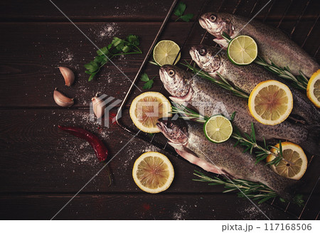 Raw rainbow trout, with lemon and herbs, on a wooden table, no people, Raw rainbow trout, with lemon and herbs, on a wooden table, no people, 117168506