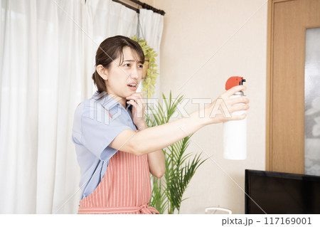 リビングに殺虫剤を噴霧する女性 リビングに殺虫剤を噴霧する女性 117169001