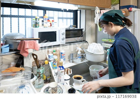 散らかったキッチンの片付けをするハウスクリーニングの女性スタッフ 散らかったキッチンの片付けをするハウスクリーニングの女性スタッフ 117169038