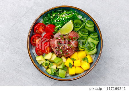 Healthy tuna poke bowl overhead top view. Poke is a traditional Hawaiian dish influenced by japanese and asian cuisine. Ahi poke is made of raw tuna chunks tossed over rice and topped with vegetables. 117169241