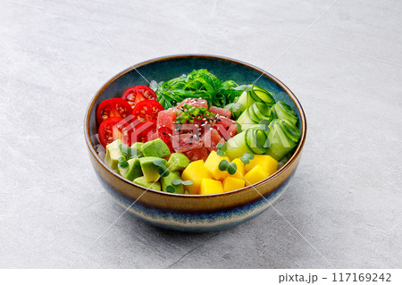 Healthy tuna poke bowl overhead top view. Poke is a traditional Hawaiian dish influenced by japanese and asian cuisine. Ahi poke is made of raw tuna chunks tossed over rice and topped with vegetables. 117169242