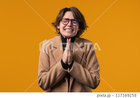 Stylish young 30s businessWoman or student lady praying, yellow background. Lady begs someone 117169258