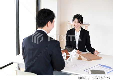 住宅模型を使い会議をする若い男女の会社員 117169275