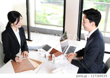 住宅模型を使い会議をする若い男女の会社員 117169535