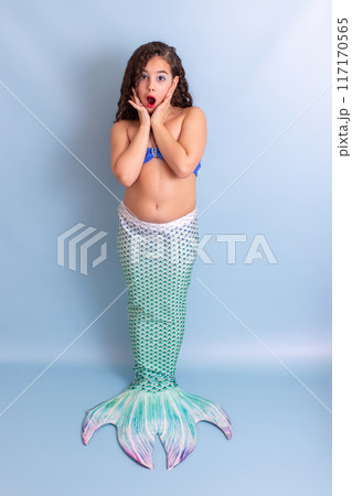 Cute surprised girl in mermaid costume stand on blue background 117170565
