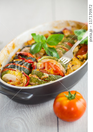 prepared baked zucchini and tomatoes in circles in a ceramic form, vegetable snack 117170972