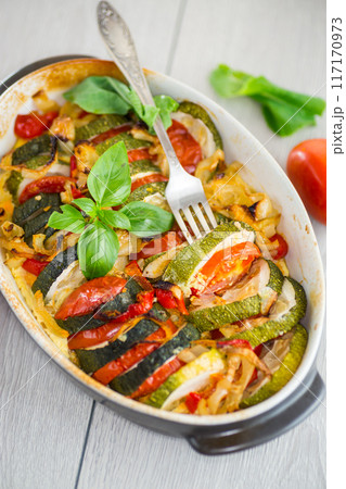 prepared baked zucchini and tomatoes in circles in a ceramic form, vegetable snack 117170973