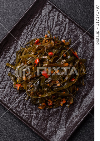 Delicious marinated seaweed with paprika, spices and salt on a dark concrete background 117171797