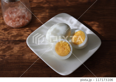 皿にのせ木製テーブルにおいたゆで卵と岩塩 117173106