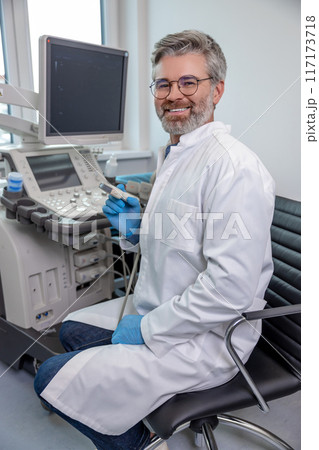 Male gray-haired professional working on a ultrasonography apparatus and looking confident 117173718