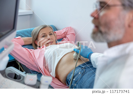 Gray-haired male doctor working with patient and making ultrasonography Gray-haired male doctor working with patient and making ultrasonography 117173741
