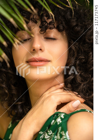 Dreaming woman wearing green dress among tropical leaves Dreaming woman wearing green dress among tropical leaves 117173745