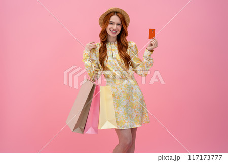 Pretty young woman in dress holding a credit card and looking contented Pretty young woman in dress holding a credit card and looking contented 117173777