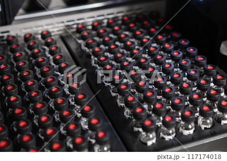 Autosampler picks up a vial with a black cap and collects samples before injecting them for HPLC analysis. 117174018