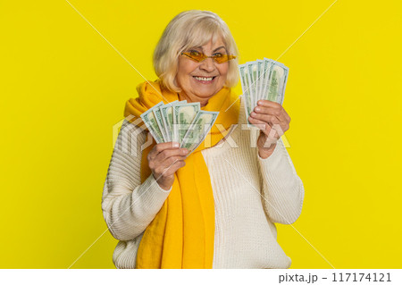 Senior old winner woman holding fan of cash money dollar banknotes celebrate dance, success pension 117174121