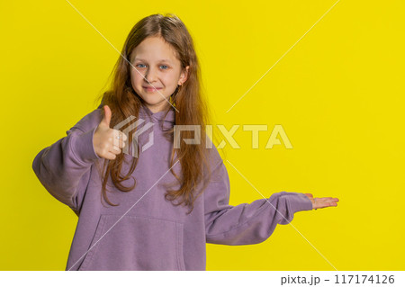 Child girl kid showing thumbs up and pointing on blank space place for advertisement promotion logo 117174126