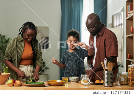 Child tasting food from wooden spatula 117174321