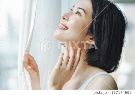 朝窓際でカーテンを開ける女性 117174699