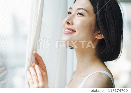朝窓際でカーテンを開ける女性 朝窓際でカーテンを開ける女性 117174700