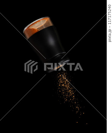 Chilli seasoning powder flavor falling from shaker bottle, red chilli and seasoning powder splash in mid air. Seasoning powder shaker spice up taste of food over black background isolated 117175240