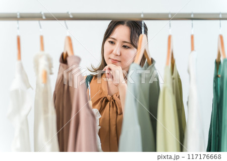 家・洋服屋・アパレルショップで洋服を選ぶ女性（ファッション・ショッピング） 117176668