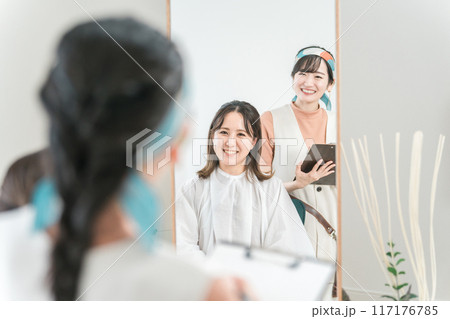 美容室・ヘアサロンでヘアスタイル・髪型を相談する客の女性とカウンセリングする美容師 117176785