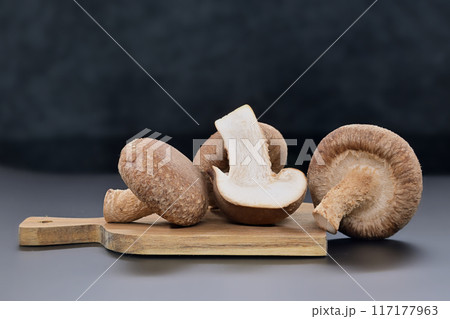 Shiitake mushrooms on cutting board over dark background 117177963