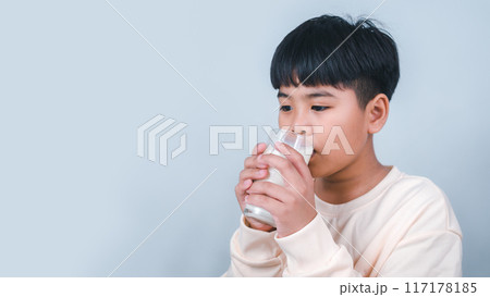 Concept of happy good nutrition, Portrait of a little young handsome kid boy in cream color shirt, Hold drinking milk box mockup, Isolated on white background. 117178185