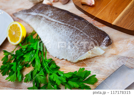 Fresh cod fillet with parsley on wooden board 117178315