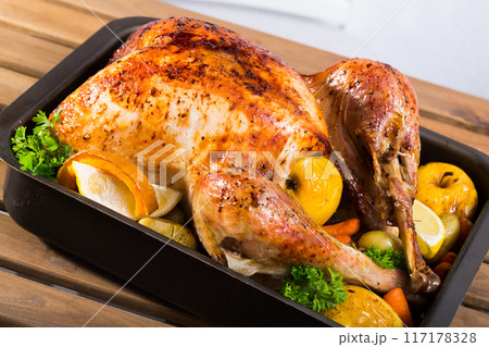 Close up of tasty cooked homemade turkey with apples, lemon and greens 117178328