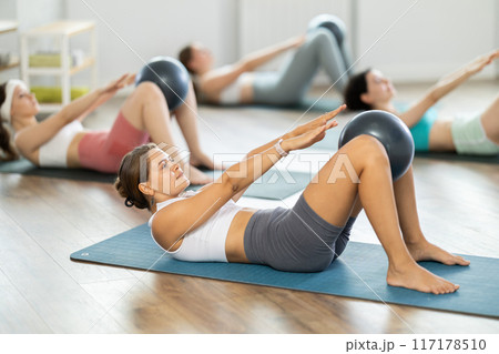 Young girl doing press with softball band between legs lying on the floor Young girl doing press with softball band between legs lying on the floor 117178510