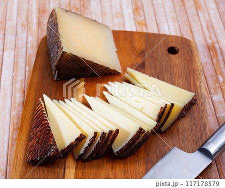 Slices of semi-hard spanish sheep cheese on desk Slices of semi-hard spanish sheep cheese on desk 117178579