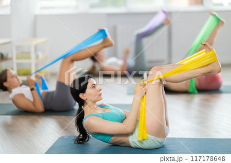 Group of young women doing pilates with band Group of young women doing pilates with band 117178648