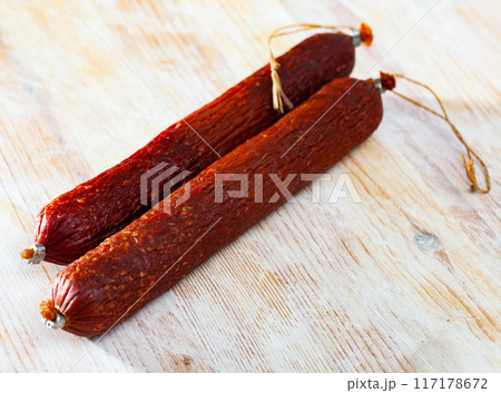 Smoked sausage on wooden surface 117178672