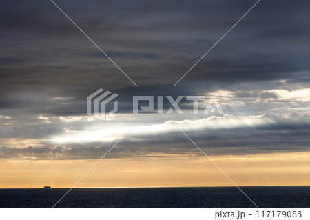 The sunrise creates a scenic view with dramatic cloud cover over the ocean horizon 117179083