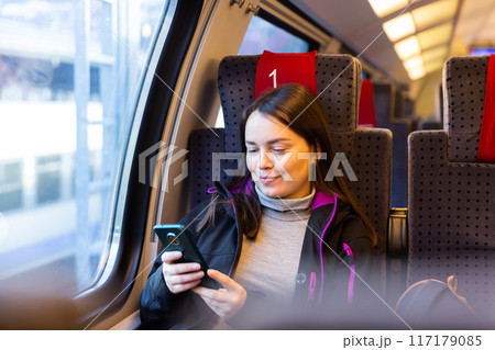 Cheerful woman chatting on mobile phone while traveling in train 117179085