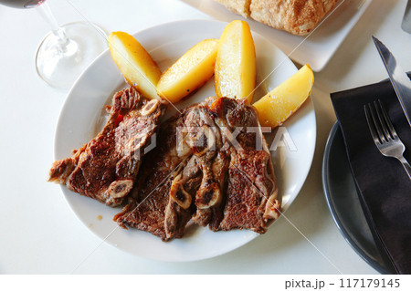 Tasty veal kebab and baked potatoes served at plate Tasty veal kebab and baked potatoes served at plate 117179145