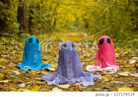 Halloween holiday concept. Handmade colorful ghosts made from bandages and glue in autumn forest background. Children's art project. DIY Halloween holiday concept. Handmade colorful ghosts made from bandages and glue in autumn forest background. Children's art project. DIY 117179514