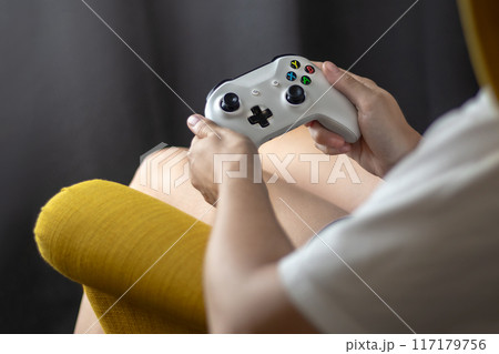 The woman is holding a white jostic, joystick, navigation key, cursor buttons, navigation control. She plays the game on the console. Close up 117179756