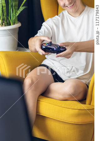 The woman is holding a white jostic, joystick, navigation key, cursor buttons, navigation control. She plays the game on the console. vertical The woman is holding a white jostic, joystick, navigation key, cursor buttons, navigation control. She plays the game on the console. vertical 117179843
