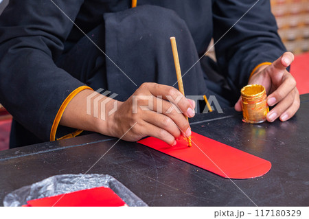Human using calligraphy brush painting on lucky money red envelope Human using calligraphy brush painting on lucky money red envelope 117180329