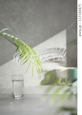 A gray-toned tile background with various props with sunlight coming through the window. 117180875