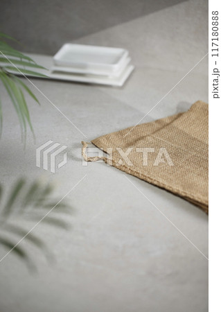 A gray-toned tile background with various props with sunlight coming through the window. 117180888