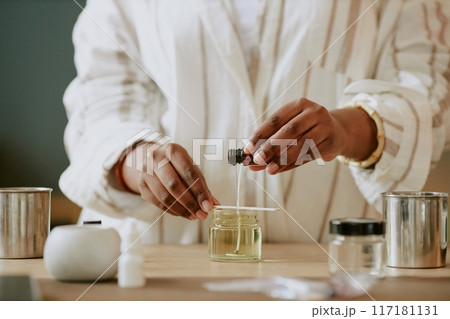 Pair of hands blending essential oils for perfume making in an artisan lab with various containers. Scene captures precision and dedication of the craft without revealing identity 117181131