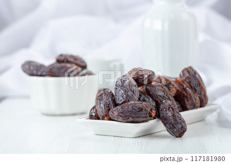 Dates in white dish on a white table. 117181980