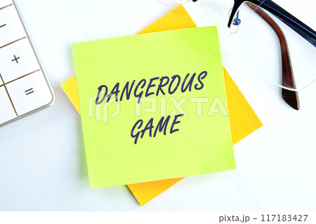 Text Dangerous game on a sticker in a composition with a calculator and glasses on top on a white background Text Dangerous game on a sticker in a composition with a calculator and glasses on top on a white background 117183427